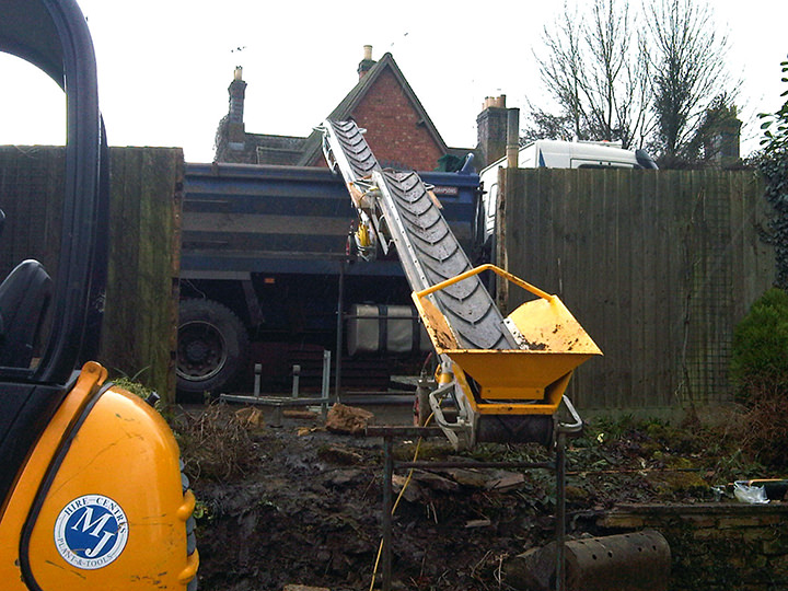 Small conveyor belt loads directly from the basement and onto a tipper truck where you can't reach with an excavator.